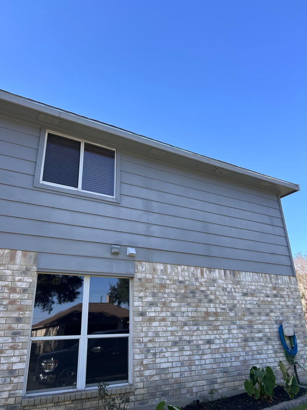 Exterior view of a light gray house showing a clear blue sky above.